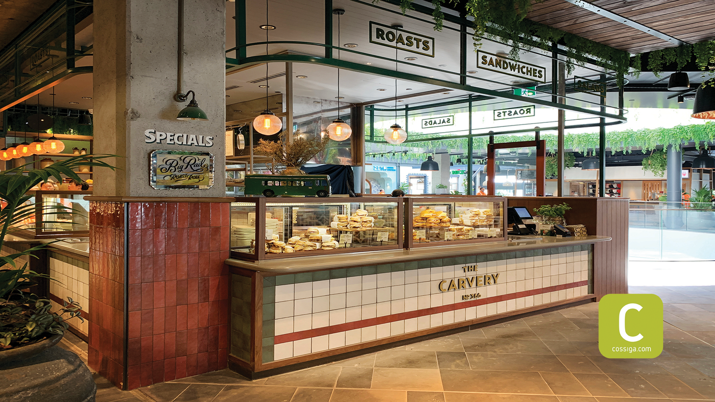 Bakery counter with display cases and signs in a modern interior setting.